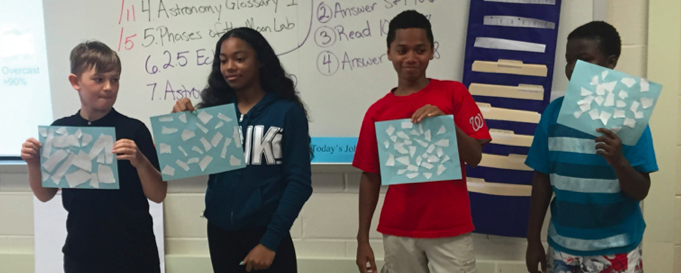 Students stand with cloud cover activity pages