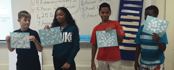 Students stand with cloud cover activity pages